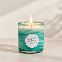 Lit UpCandle in an upcycled teal swirl glass container, labelled Upcycled with love by CandleXchange