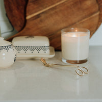 wick trimmer for candle on table with lit candle