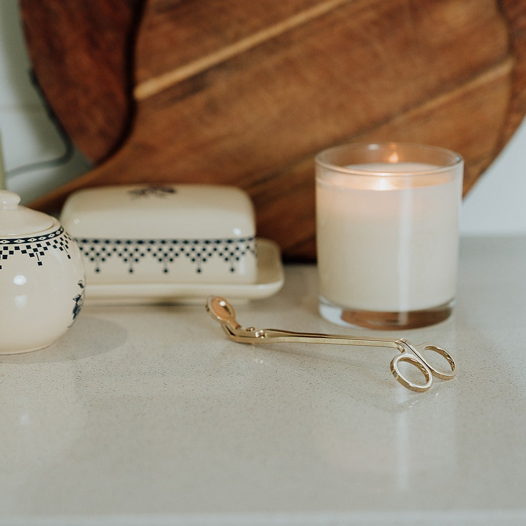 wick trimmer for candle on table with lit candle
